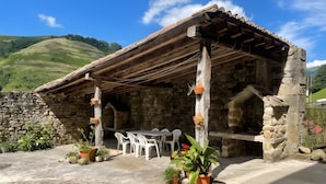 Ein Steinhaus mit Holzdach, Außenbestuhlung und Blumentöpfen.