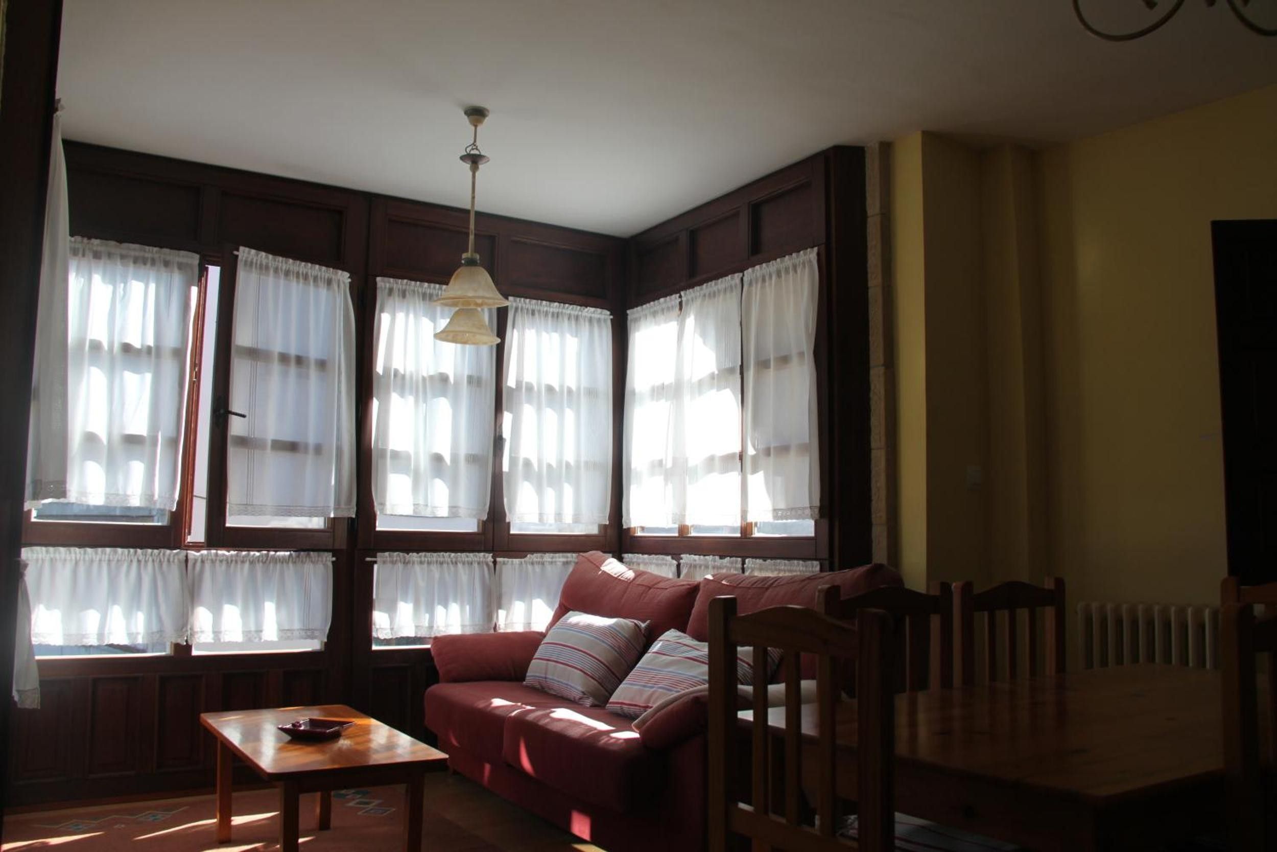 Una habitación con un sofá de madera, una mesa y un radiador.