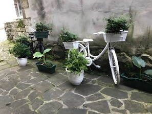A bicycle with potted plants attached to the front, parked on a stone-paved surface.