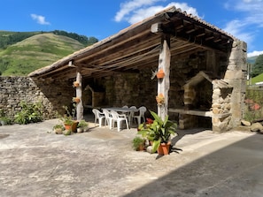 Un edificio de piedra con techo de madera, mesas al aire libre y plantas en macetas.