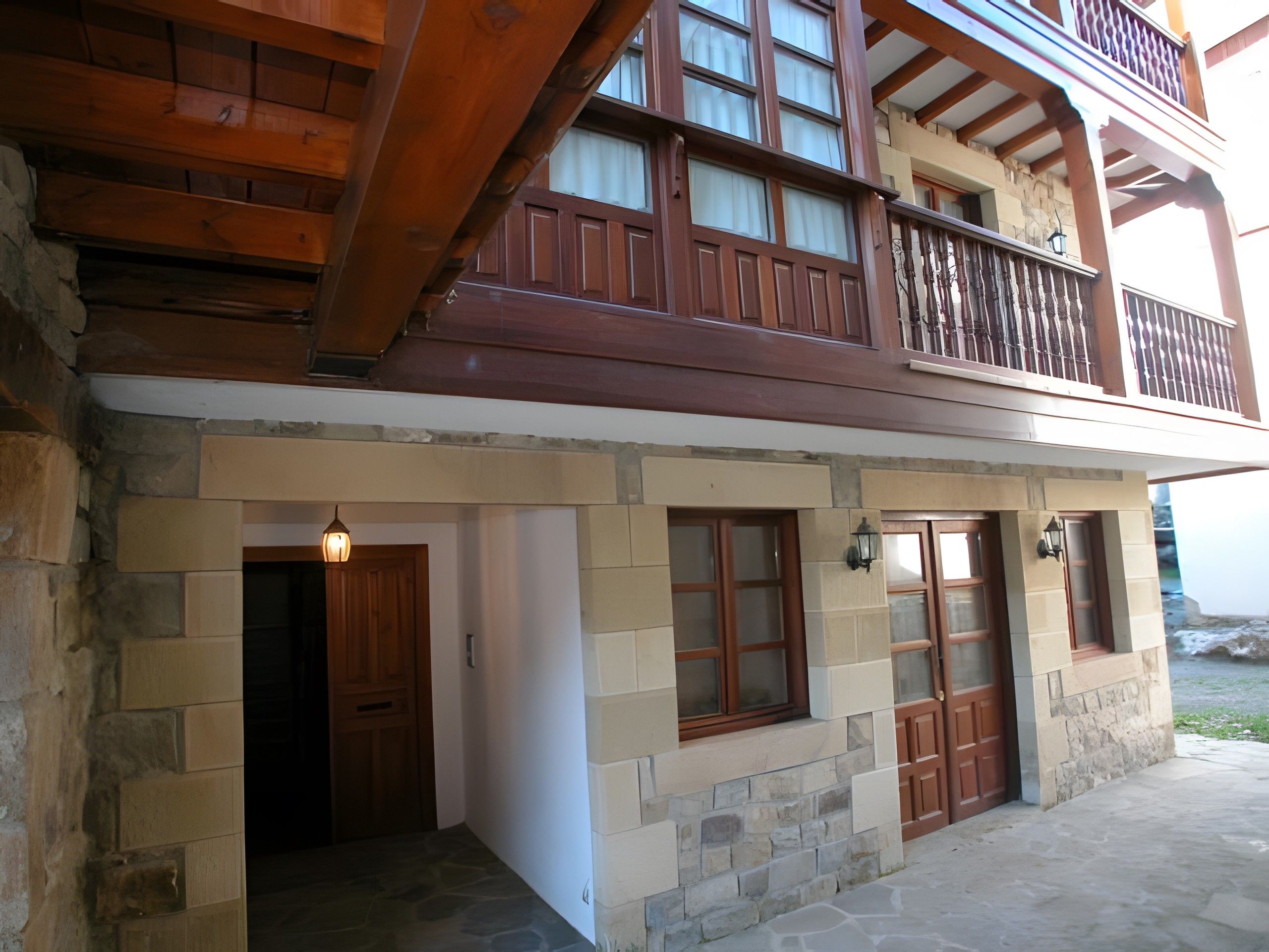 A two-story building with a stone facade, wooden balconies, and a stone entrance.