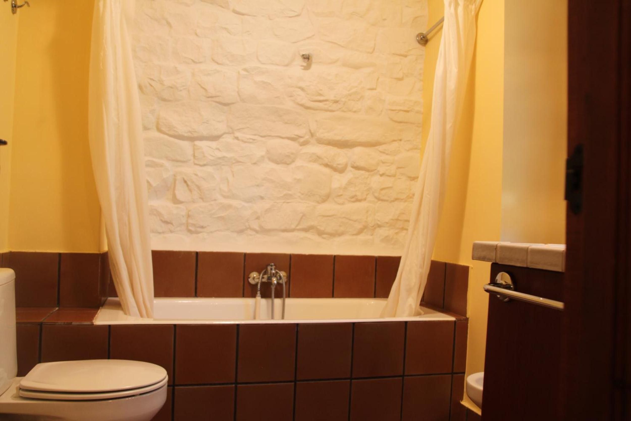 Un bagno con parete effetto pietra, una vasca e un water.