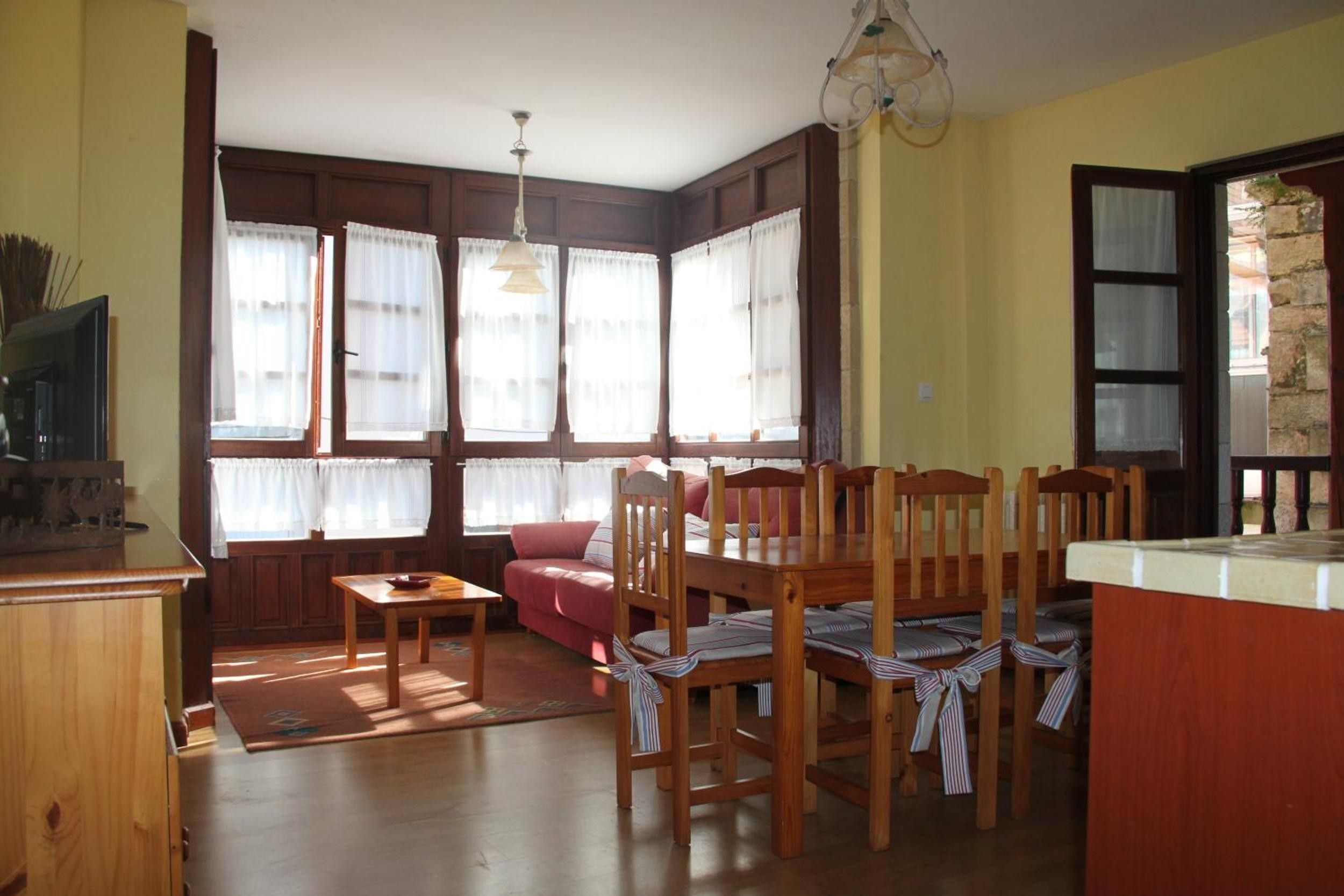 Un salón acogedor con un sofá, una mesa de comedor de madera, sillas y una zona de cocina con mostrador.