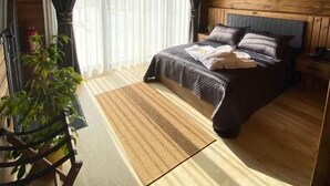 A wooden-paneled room with a bed, a chair, and a plant.
