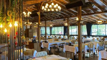 A restaurant with wooden beams, chandeliers, and tables set for dining.