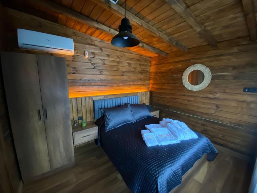 Una habitación tipo cabaña de madera con una cama, un armario y un ventilador de techo.