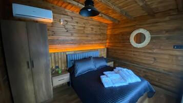 Una habitación tipo cabaña de madera con una cama, un armario y un ventilador de techo.