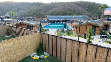 A pool area with a wooden fence, a small tree, and a building with a sign.