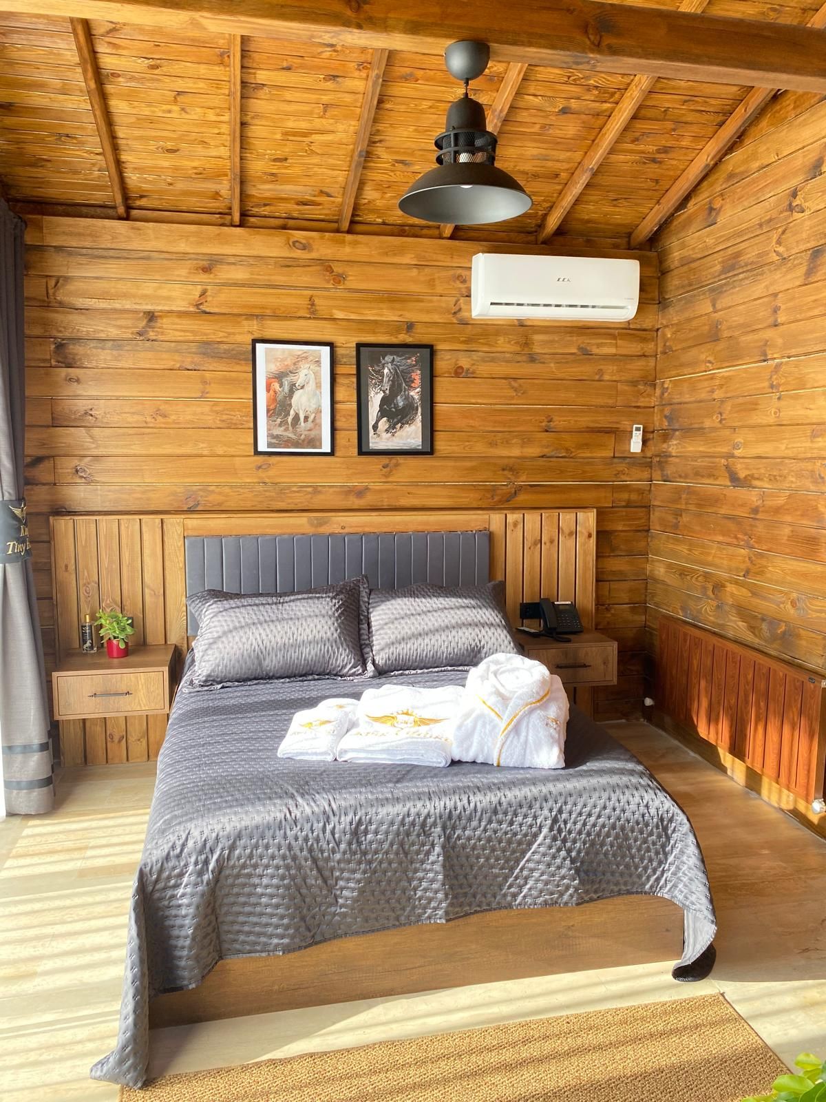 Una habitación con paneles de madera, una cama, dos cuadros enmarcados, una lámpara de techo y un radiador.