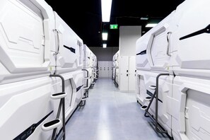 A row of white, modern-looking, rectangular units with handles, possibly a row of portable toilets or similar facilities, in a clean, well-lit corridor.