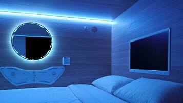 Een moderne slaapkamer met een bed, een ronde spiegel en een tv aan de muur.