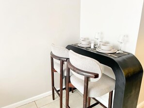 A dining area with a black table, two chairs, and a white wall. - Marvelous 1-bedroom apartment in the heart of Kiambu road (Kiambu)