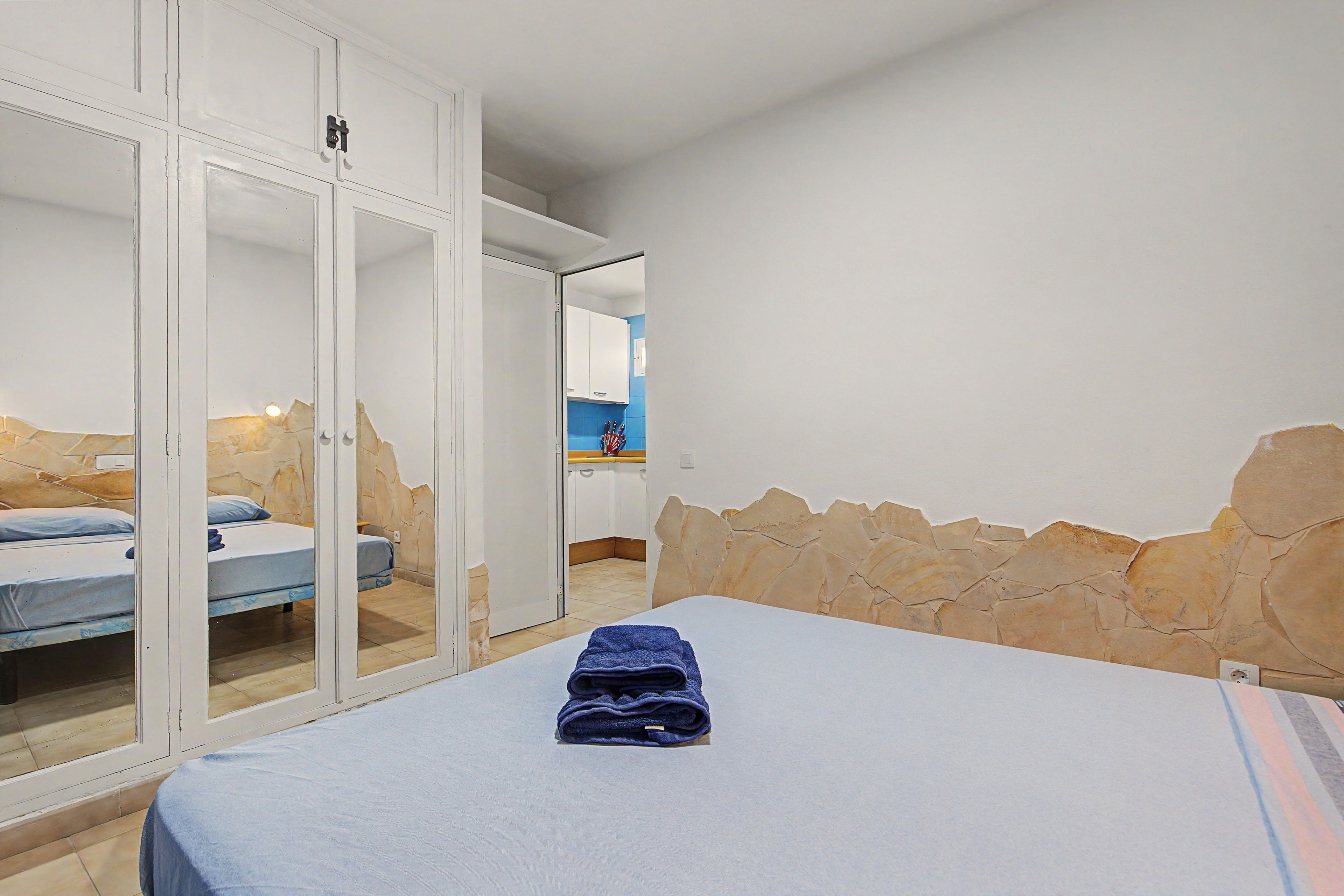 Une chambre à coucher avec un lit, une armoire et une salle de bain visible à travers une porte ouverte.