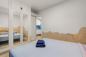 A bedroom with a bed, a wardrobe, and a bathroom visible through an open door.