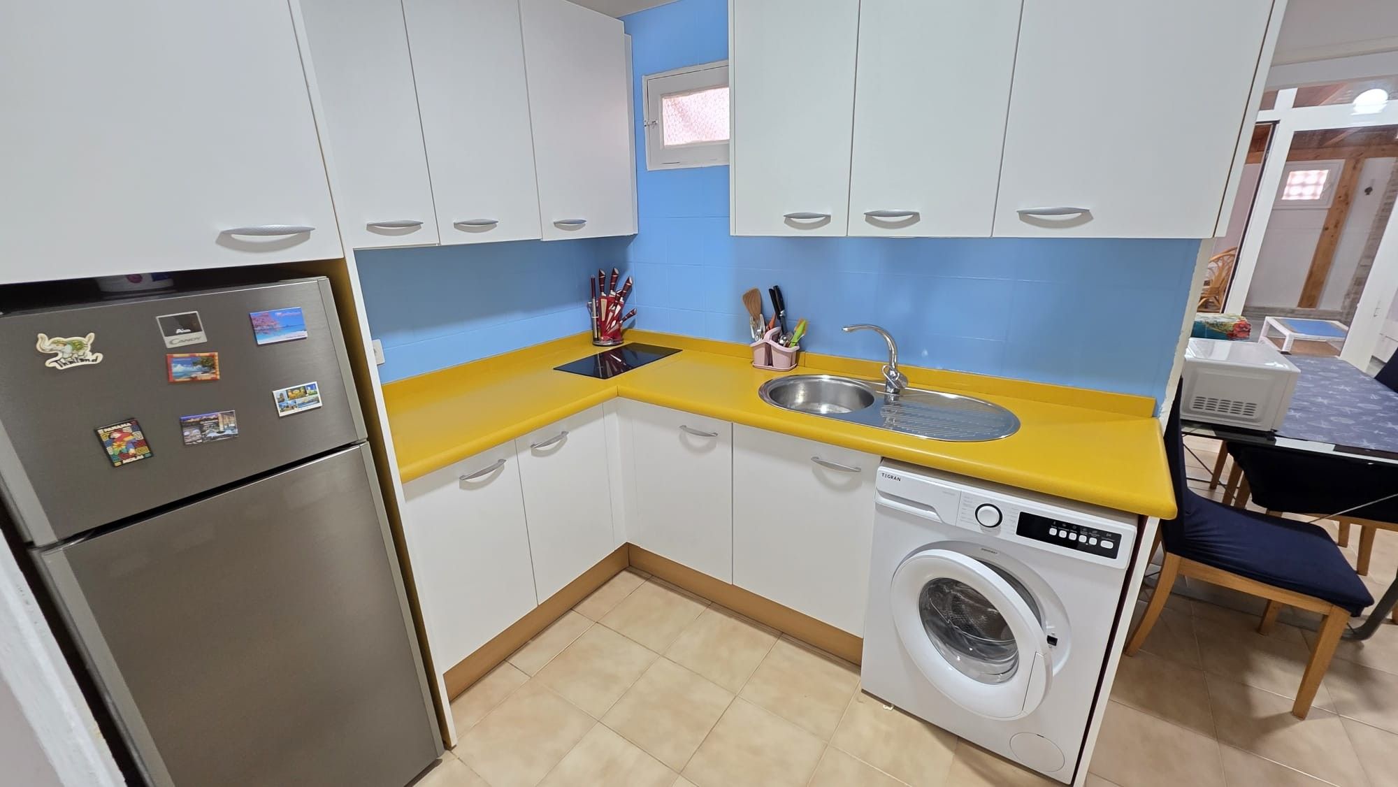 A compact kitchen with a washing machine, a refrigerator, and a sink.