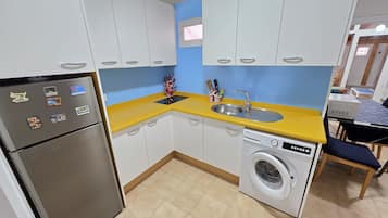 A compact kitchen with a washing machine, a refrigerator, and a sink.