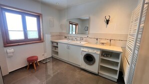 A modern bathroom with a washing machine, a sink, a mirror, and a red stool. - Vrbo Property (Oberreute)