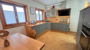 Eine Küche mit Holzausstattung, einem Esstisch und einem Fernseher über der Arbeitsfläche.
