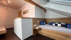 Ein kleines Zimmer mit Bett, Schreibtisch und Fenster.