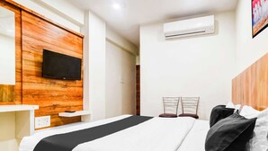A hotel room with a bed, a mounted television, an air conditioning unit, and a painting on the wall. - Collection O Indore Gandhi Hall (Indore)