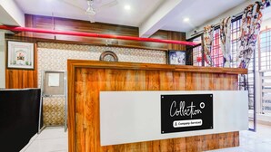 A reception desk with a wooden finish, a clock, and a sign indicating it is company-serviced. - Collection O Indore Gandhi Hall (Indore)