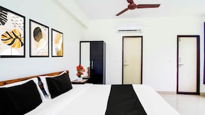 A hotel room with a bed, a wardrobe, a door, an air conditioning unit, and framed artwork on the wall. - Collection Rushikonda Beach Near GITAM (Visakhapatnam)