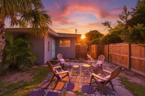 A patio with outdoor furniture and a small building, surrounded by a wooden fence and vegetation. - Fenced Backyard 2BR Pet Friendly and Sleeps 6 (Clearwater)