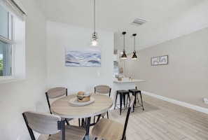 A dining area with a round table, chairs, and a painting on the wall. - Fenced Backyard 2BR Pet Friendly and Sleeps 6 (Clearwater)