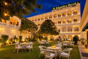 A hotel with a courtyard, outdoor seating, and a large building with arched windows and balconies. - Khandwa Haveli – A Boutique Heritage Hotel, Jaipur (Jaipur)