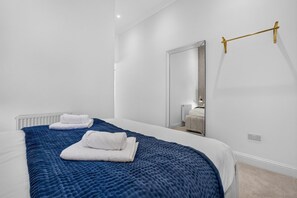 A hotel room with a bed, a large mirror, and a towel rack. - Seaview Largs - 1 Bedroom Ground Floor Apartment (Largs)