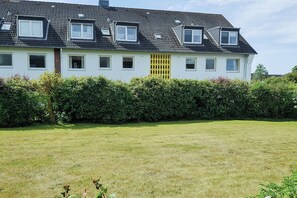 Ein zweigeschossiges Wohngebäude mit zahlreichen Fenstern, einem flachen Dach und einem gepflegten Rasen davor.