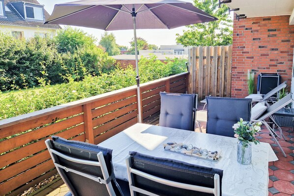 Eine Außenpatio mit Tisch, Stühlen und Sonnenschirm.