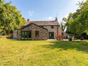 A stone house with a large front porch, a chimney, and a well-maintained lawn. - The Homestead (Newquay)