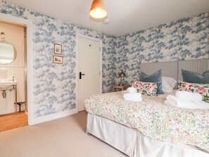 A bedroom with a bed, a bedside table, a lamp, and a door. - The Homestead (Newquay)