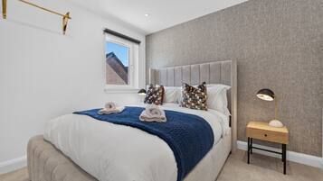 A modern bedroom with a large bed, a bedside table with a lamp, and a window with a view.