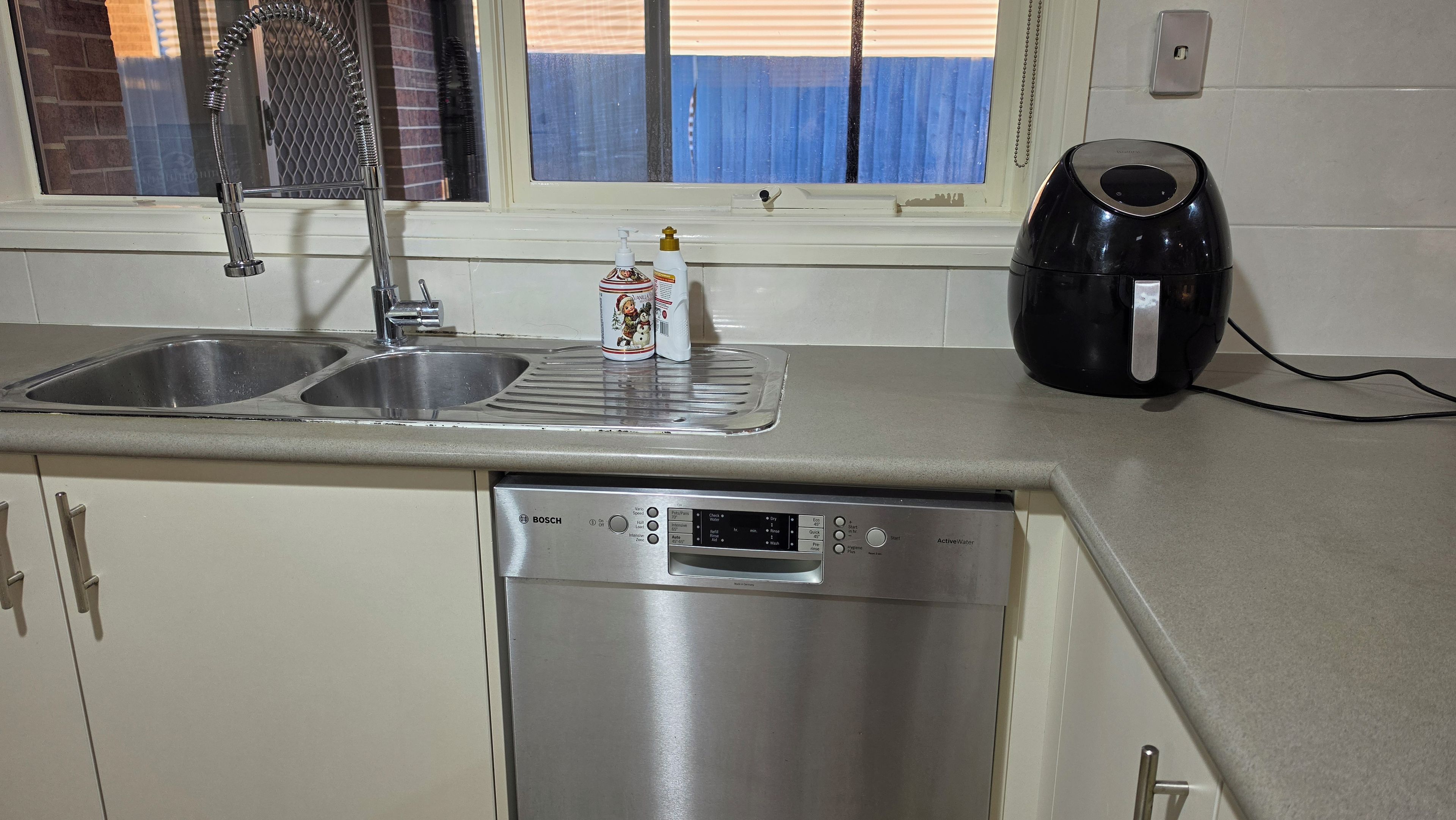 A kitchen with a Bosch dishwasher, a double sink, and a kettle.
