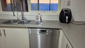 A kitchen with a Bosch dishwasher, a double sink, and a kettle.
