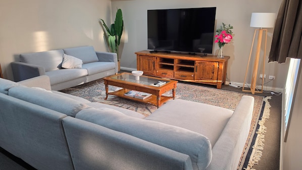 A living room with a sofa, coffee table, TV, wooden cabinet, and a lamp.