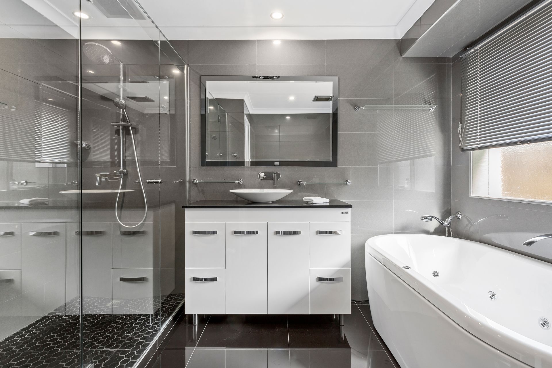Une salle de bain moderne dotée d’une douche à parois de verre, d’une baignoire sur pieds et d’un meuble-lavabo avec un grand miroir.