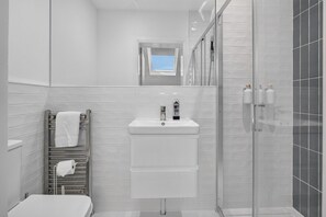 Ein modernes Badezimmer mit Toilette, Waschbecken und Duschbereich.