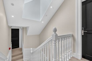 Eine Treppe mit weißen Balustraden und einer dunklen Tür am Oberende.
