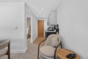 A modern living room with a sofa, a wooden coffee table, and a remote control on it. - Seaview Largs - 1 Bedroom Apartment (Largs)