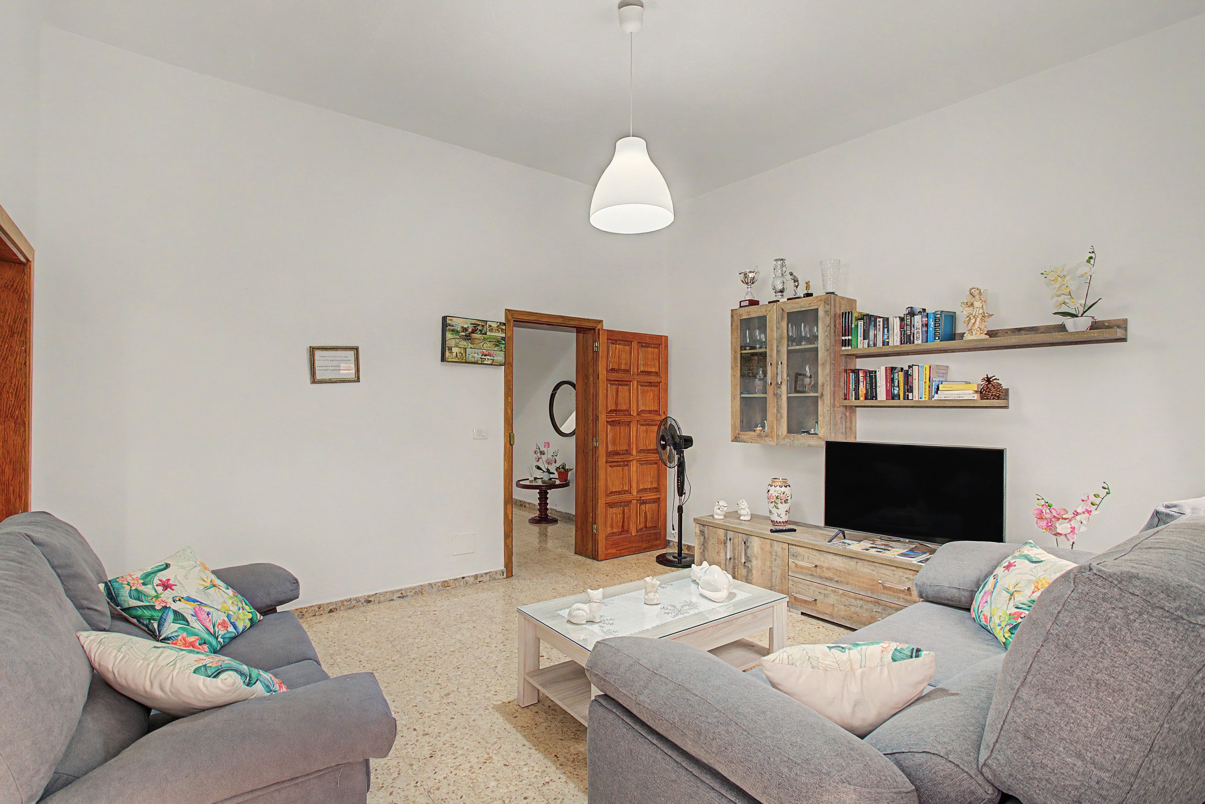 Una sala de estar con sofá, mesa de centro, televisor y estantería.