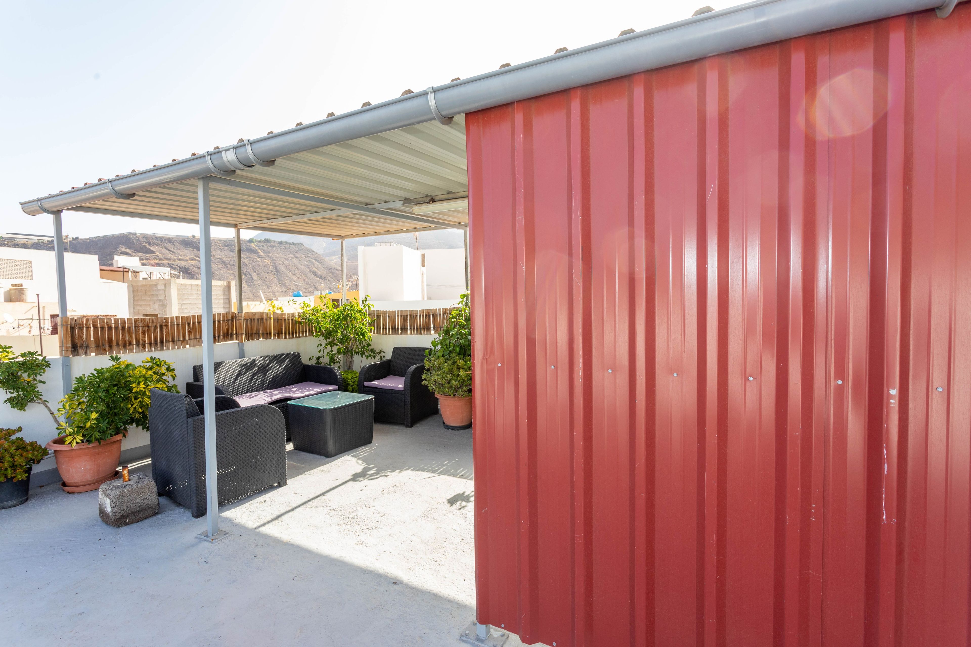 A rooftop patio with outdoor furniture and potted plants.