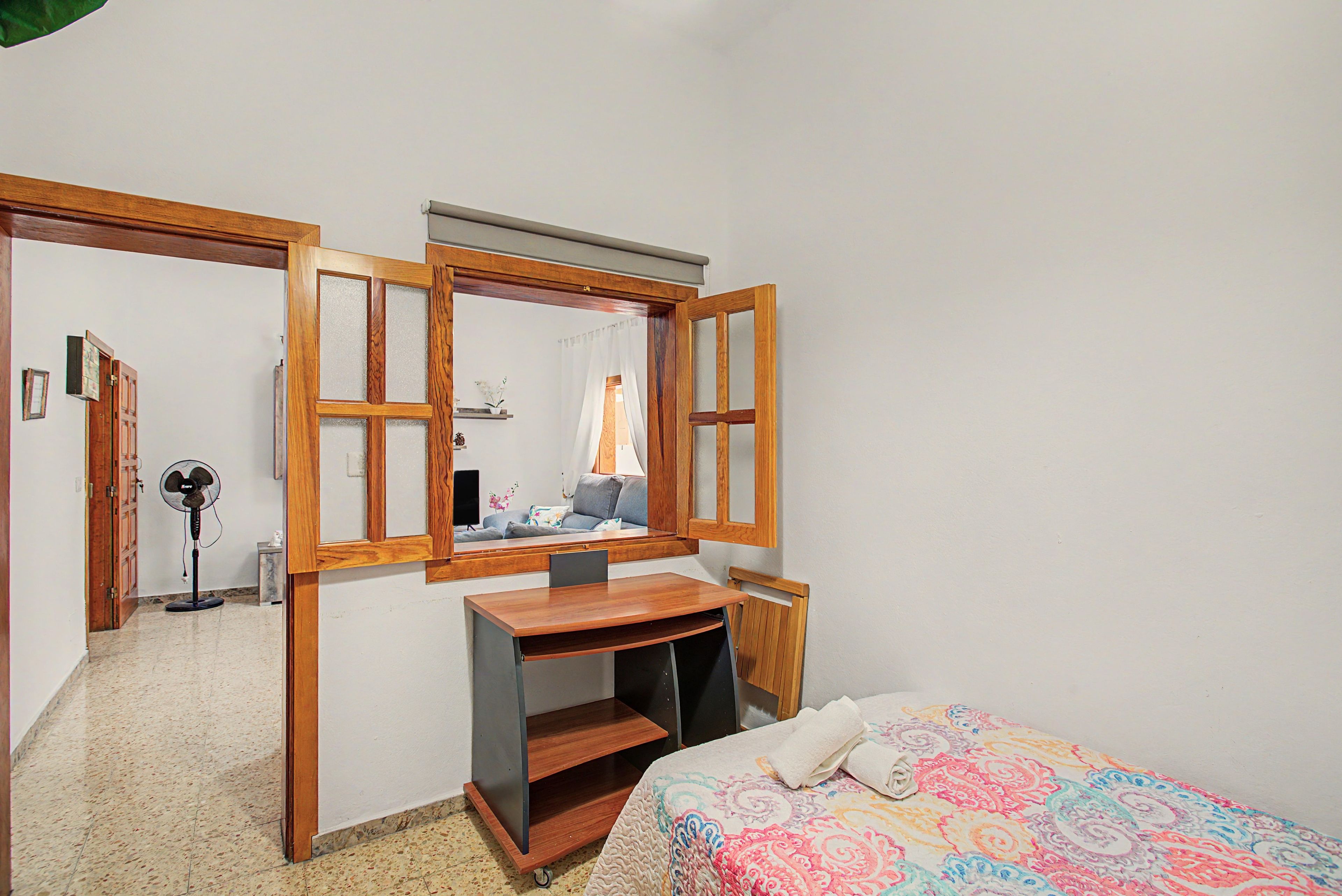Een slaapkamer met een bed, een bureau en een spiegel.