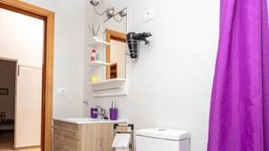 Ein modernes Badezimmer mit Toilette in Weiß, einem Holzkosmetikschrank, einem Spiegel und einem violetten Duschvorhang.