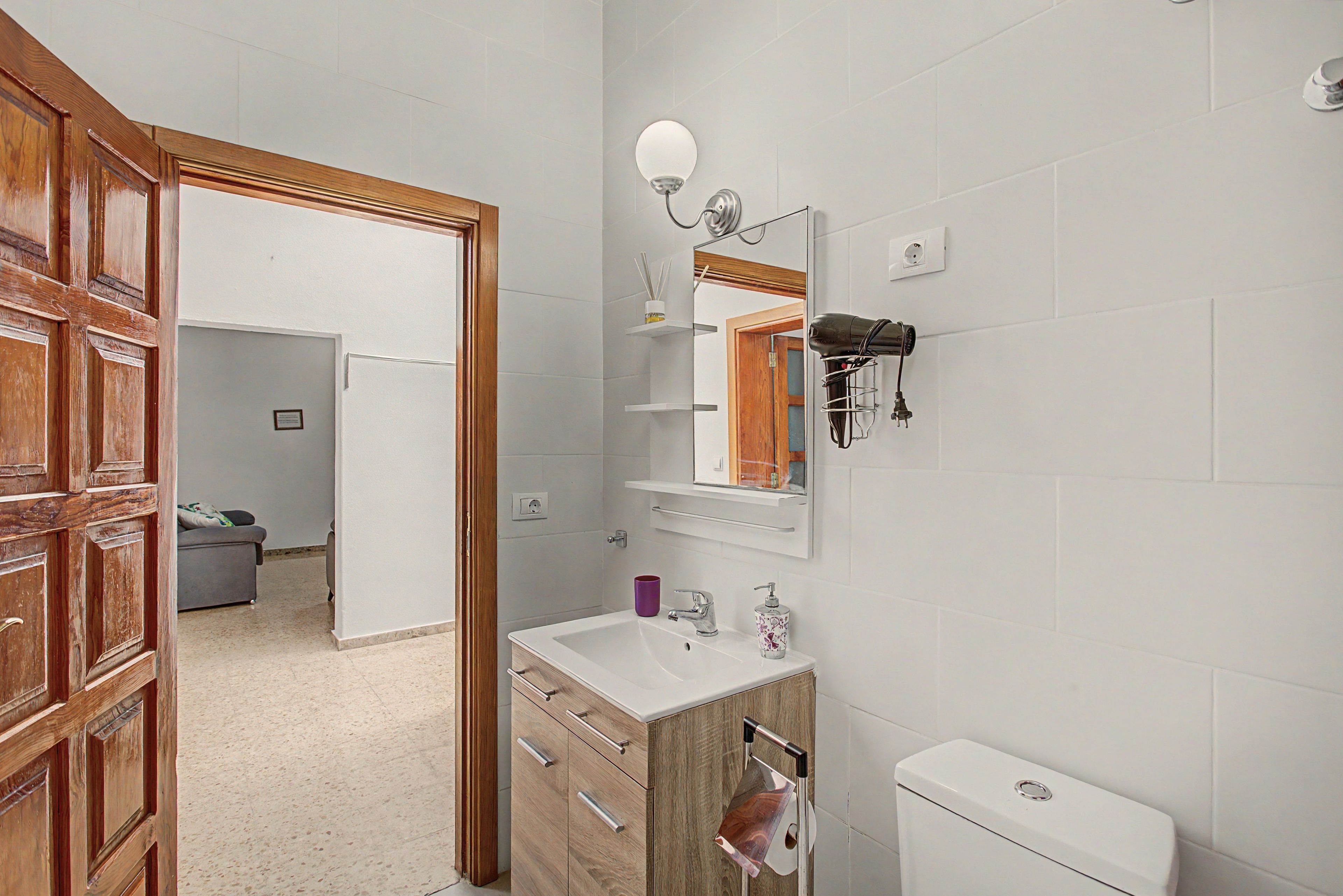 Ein Badezimmer mit Holztür, Waschbecken, Spiegel und Toilette.