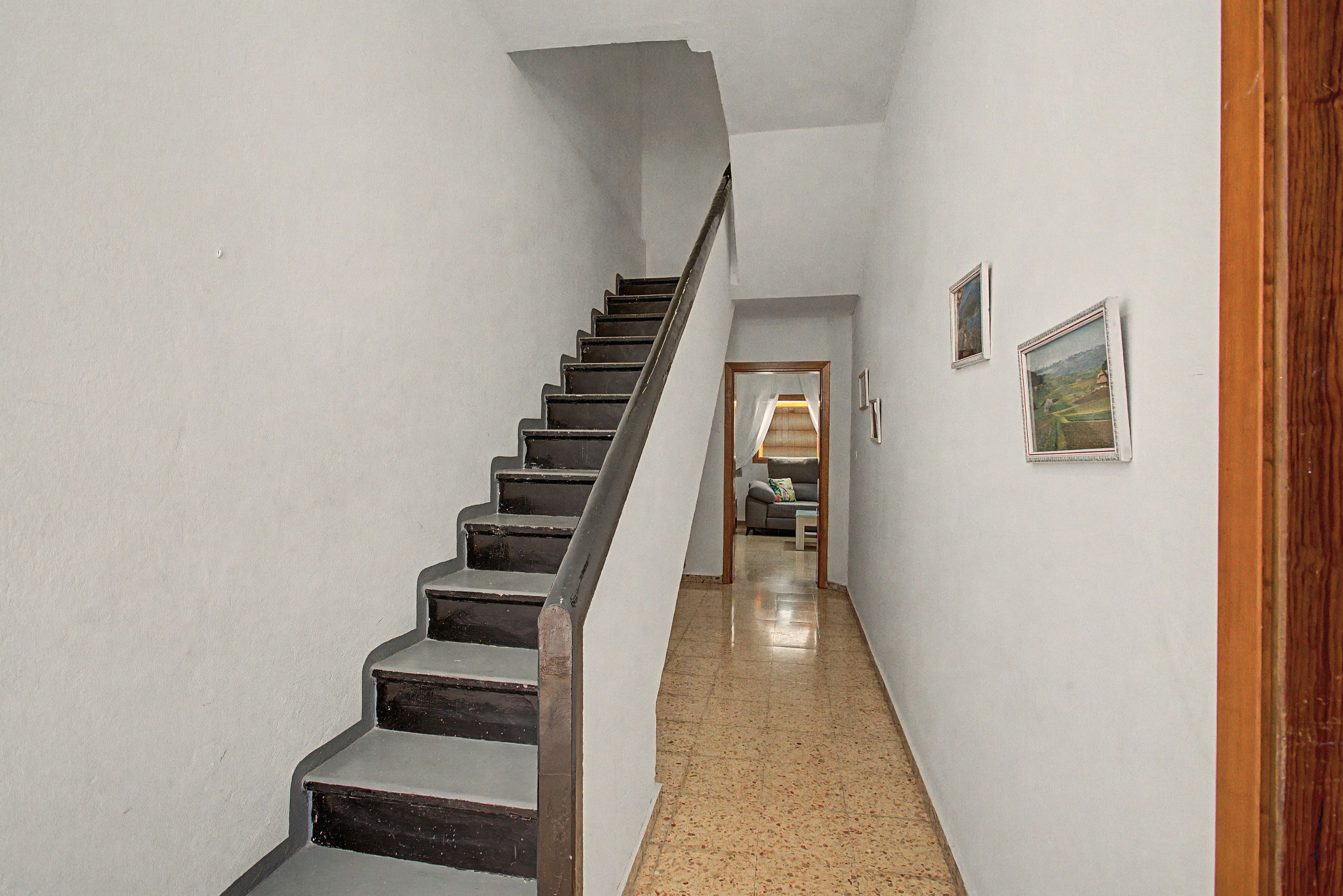 Un escalier menant à une pièce où se trouvent un canapé et un tableau accroché au mur.