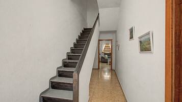Un escalier menant à une pièce où se trouvent un canapé et un tableau accroché au mur.