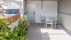 Ein überdachter Balkon mit Tisch und Stühlen, ein Holzzaun und Kübelpflanzen.